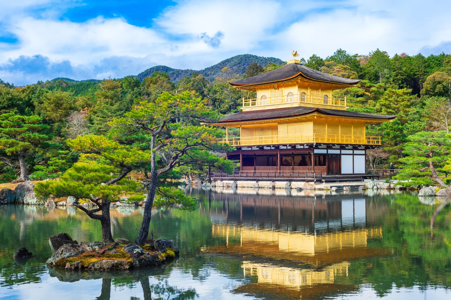 Kinkaku-ji Golden Pavilion in Kyoto, Japan, reflected on the lake with surrounding trees and mountains – a must-visit near your Kyoto hotel