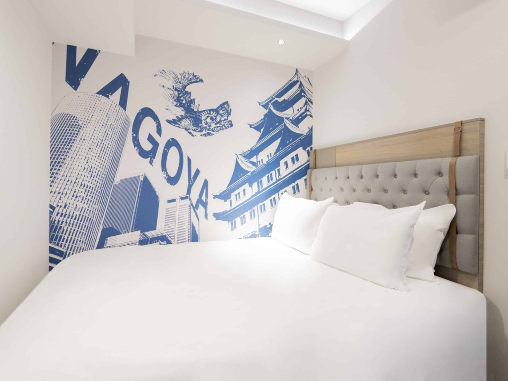 Modern guest room at Travelodge Nagoya Sakae hotel featuring comfortable bedding and Nagoya-themed wall art design near city attractions.
