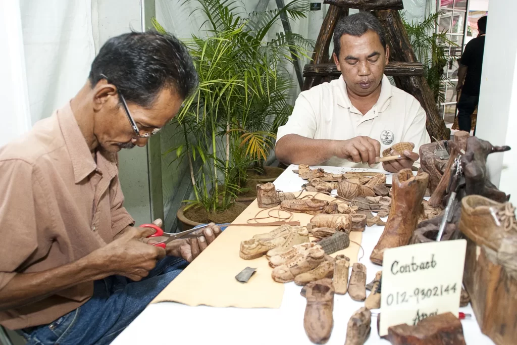 Local Malaysian artisans carving intricate wooden crafts by hand — a cultural workshop experience travelers can enjoy near their 쿠알라룸푸르 호텔 stay.