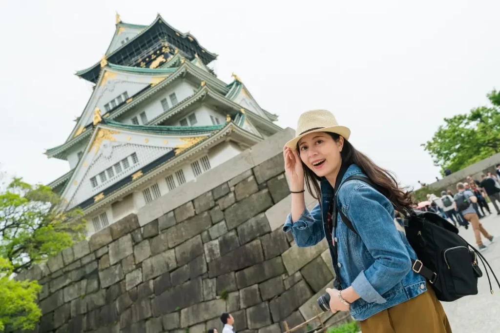 a tourist taking a photo of Osaka Castle near her Osaka Honmachi Hotel